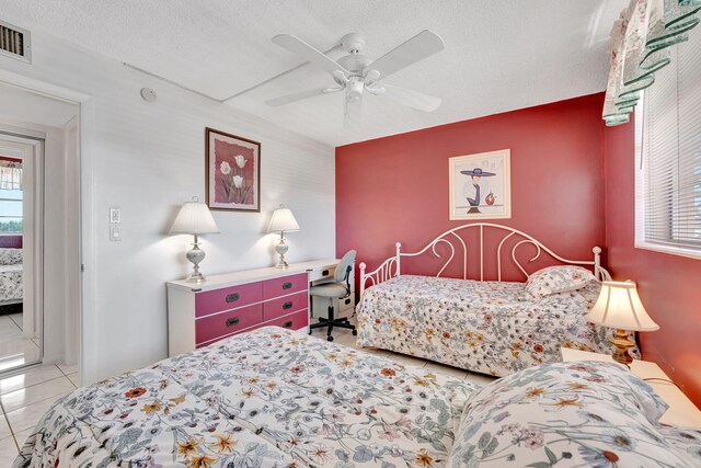 bedroom featuring ceiling fan, visible vents, tile patterned flooring, and a textured ceiling