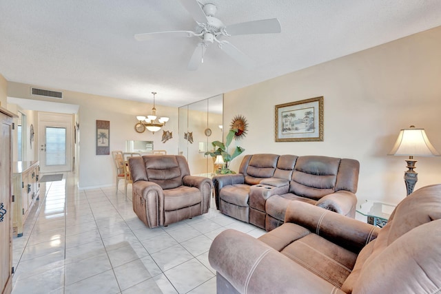living room featuring ceiling fan with notable chandelier, visible vents, light tile patterned floors, and a textured ceiling