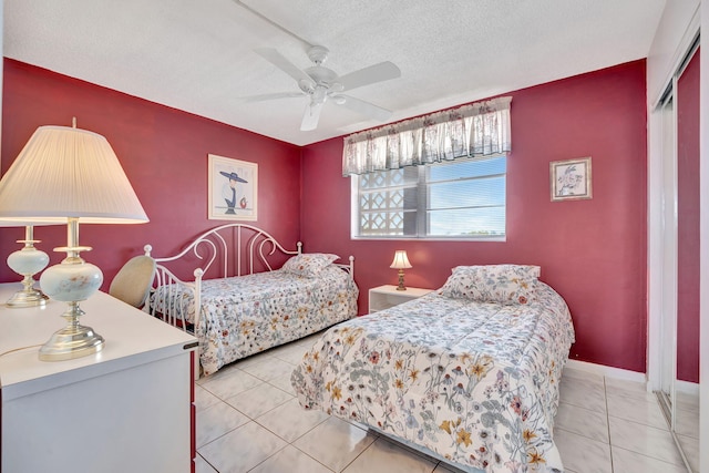 tiled bedroom featuring a ceiling fan, baseboards, a closet, and a textured ceiling