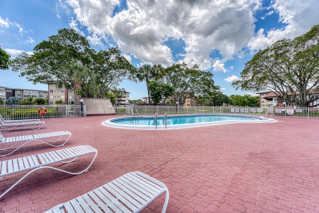 pool with a patio area and fence