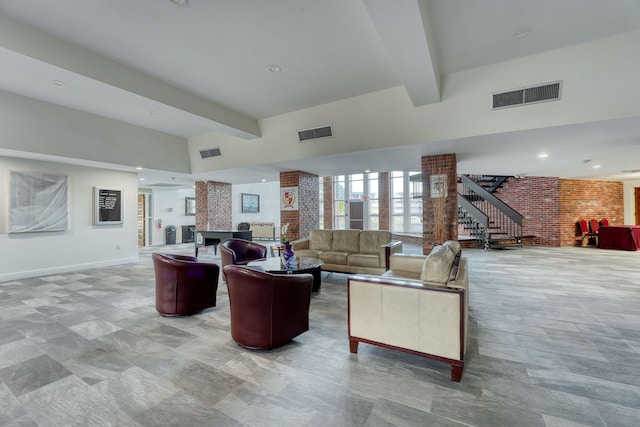 living room with visible vents, beamed ceiling, and brick wall