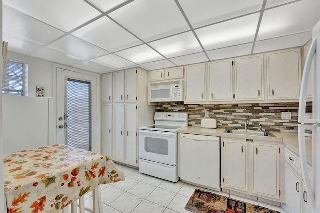 kitchen with decorative backsplash, light countertops, white appliances, a sink, and a drop ceiling