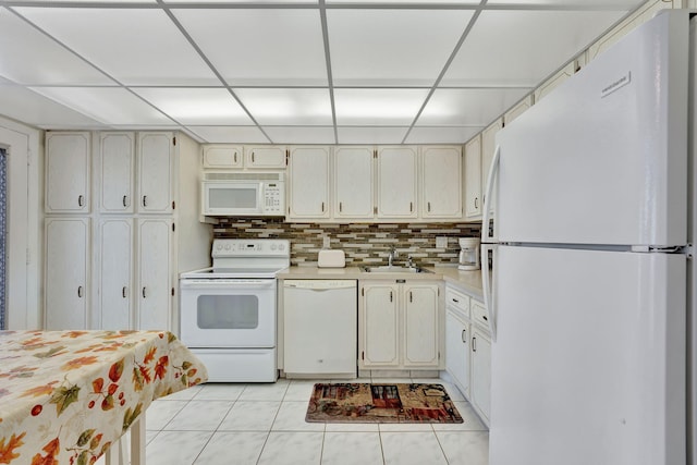 kitchen featuring light countertops, a sink, white appliances, decorative backsplash, and a paneled ceiling