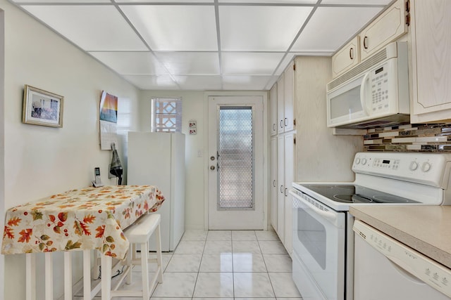 kitchen with light countertops, tasteful backsplash, white appliances, light tile patterned floors, and a paneled ceiling