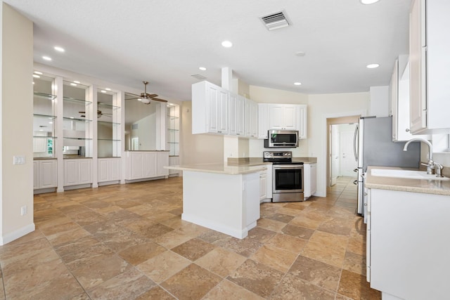 kitchen featuring appliances with stainless steel finishes, white cabinetry, stone tile flooring, and visible vents
