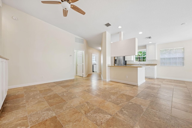 kitchen with visible vents, white cabinetry, stone tile flooring, and stainless steel fridge