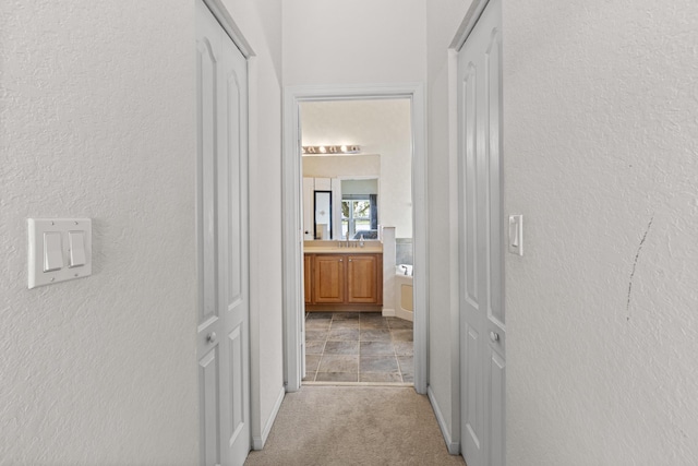 154 Berenger Walk, Royal Palm Beach, FL 33414 - corridor with light colored carpet, baseboards, a sink, and a textured wall