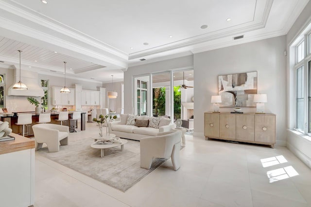living area featuring visible vents, recessed lighting, a tray ceiling, and ornamental molding