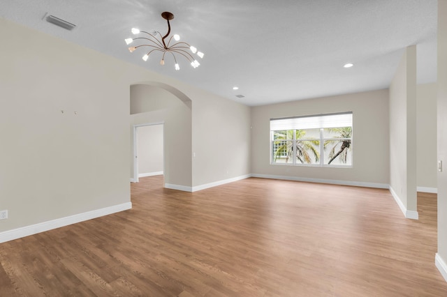 13594 Morocca Lake Ln, Delray Beach, FL 33446 - spare room featuring arched walkways, a chandelier, light wood-type flooring, baseboards, and recessed lighting