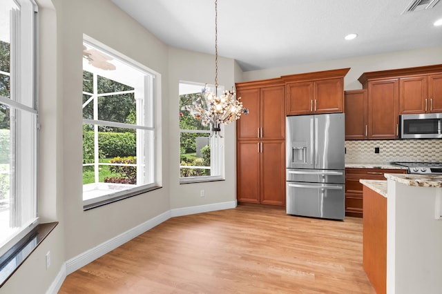 13594 Morocca Lake Ln, Delray Beach, FL 33446 - kitchen featuring stainless steel appliances, brown cabinetry, light wood-type flooring, backsplash, and decorative light fixtures