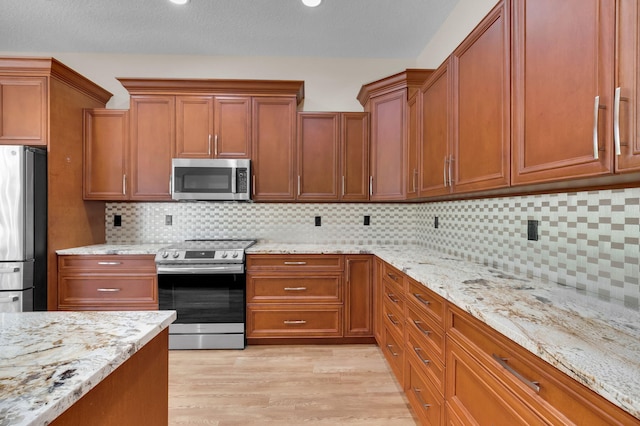 13594 Morocca Lake Ln, Delray Beach, FL 33446 - kitchen with stainless steel appliances, light wood-type flooring, brown cabinets, and light stone counters