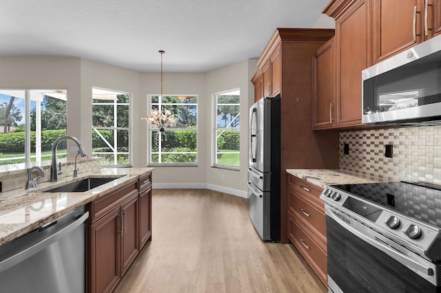 13594 Morocca Lake Ln, Delray Beach, FL 33446 - kitchen featuring appliances with stainless steel finishes, a sink, tasteful backsplash, light wood-style floors, and brown cabinets