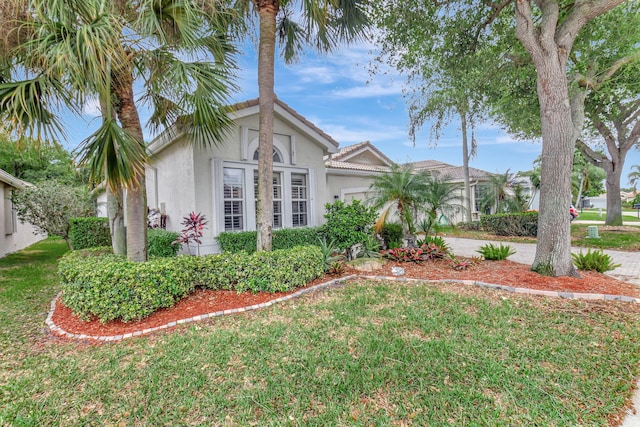 view of front of house with a front yard, driveway, an attached garage, stucco siding, and a tiled roof