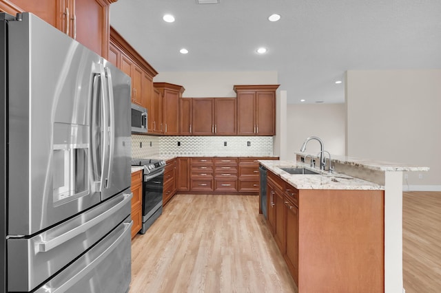 13594 Morocca Lake Ln, Delray Beach, FL 33446 - kitchen with stainless steel appliances, a sink, light wood-style flooring, brown cabinetry, and tasteful backsplash