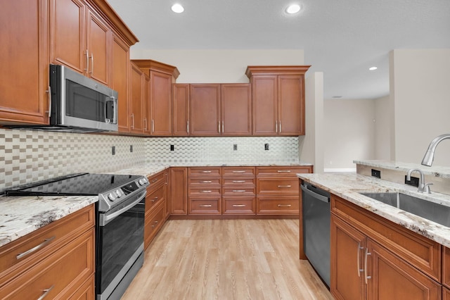 13594 Morocca Lake Ln, Delray Beach, FL 33446 - kitchen featuring appliances with stainless steel finishes, a sink, light wood finished floors, brown cabinetry, and light stone counters