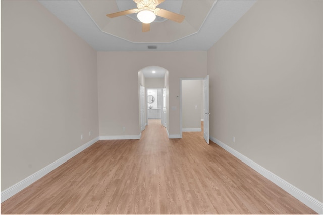 13594 Morocca Lake Ln, Delray Beach, FL 33446 - spare room featuring arched walkways, light wood finished floors, a ceiling fan, baseboards, and a tray ceiling