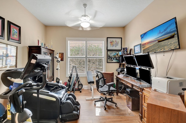 home office with baseboards, a textured ceiling, light wood-style flooring, and a ceiling fan