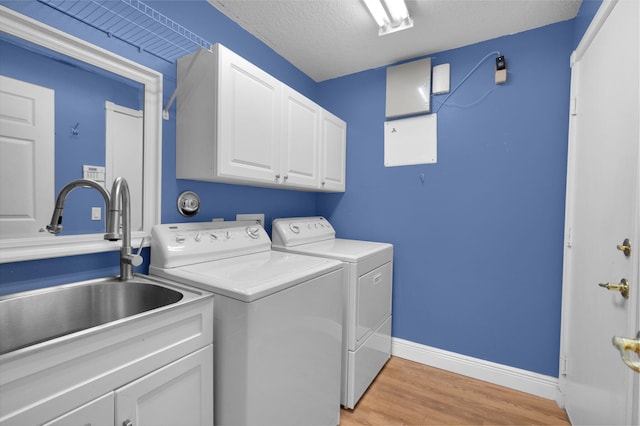 13594 Morocca Lake Ln, Delray Beach, FL 33446 - washroom with cabinet space, washer and dryer, light wood-type flooring, baseboards, and a textured ceiling