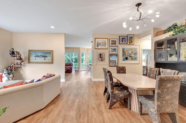 dining area with an inviting chandelier, baseboards, and light wood finished floors