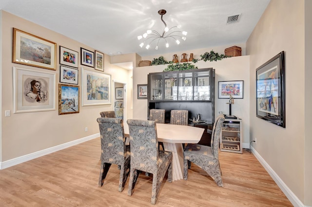 dining space with a notable chandelier, baseboards, visible vents, and light wood-type flooring
