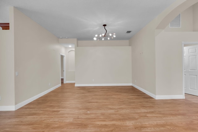 13594 Morocca Lake Ln, Delray Beach, FL 33446 - empty room with a chandelier, arched walkways, light wood-style floors, and baseboards