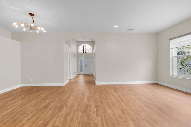 13594 Morocca Lake Ln, Delray Beach, FL 33446 - empty room with a chandelier, arched walkways, light wood-style floors, baseboards, and recessed lighting