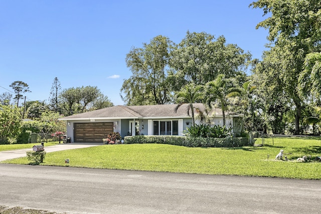 ranch-style home featuring an attached garage, driveway, a front yard, and fence