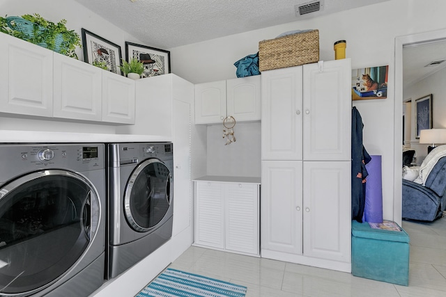 washroom with visible vents, cabinet space, a textured ceiling, and independent washer and dryer