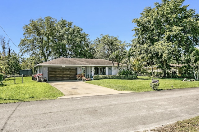 ranch-style house featuring a front yard, fence, an attached garage, stucco siding, and concrete driveway