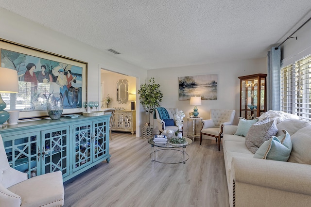 living room featuring visible vents, a textured ceiling, and wood finished floors