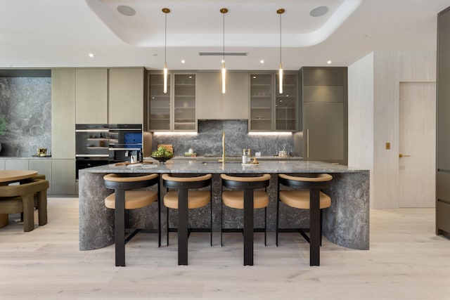 1246 George Bush, Delray Beach, FL 33483 - kitchen featuring light wood-style flooring, modern cabinets, a breakfast bar area, and a tray ceiling