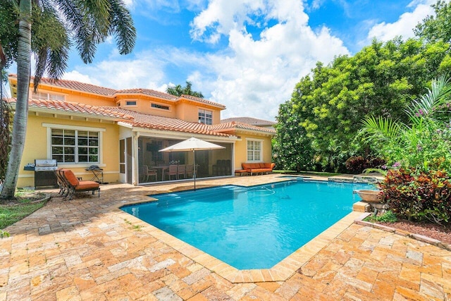 swimming pool featuring a patio area, a sunroom, and grilling area