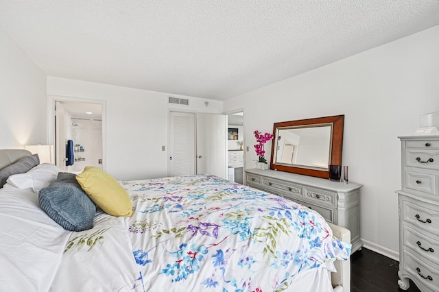 2400 Presidential Way Unit 302, West Palm Beach, FL 33401 - bedroom with dark wood-type flooring, baseboards, a textured ceiling, and ensuite bath