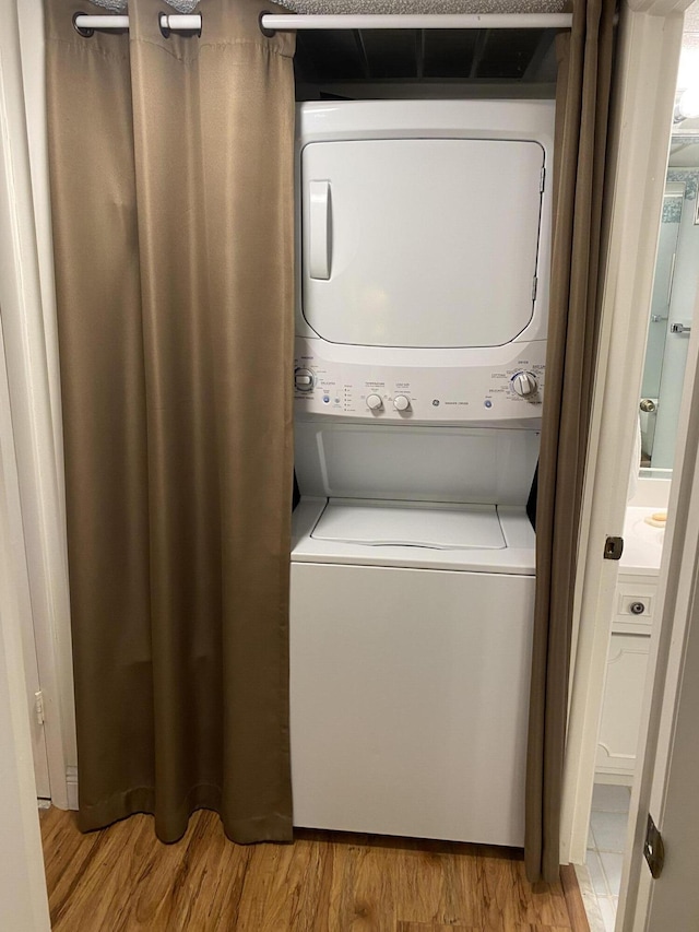 laundry area with stacked washing machine and dryer and wood finished floors