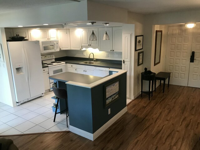 1800 SE Saint Lucie Blvd Unit 5203, Stuart, FL 34996 - kitchen featuring white appliances, a sink, light wood-style flooring, white cabinets, and hanging light fixtures