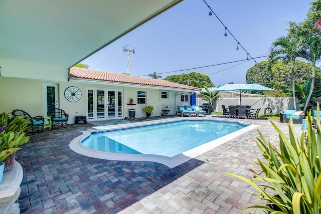 view of pool featuring fence, a fenced in pool, outdoor dining space, french doors, and a patio area
