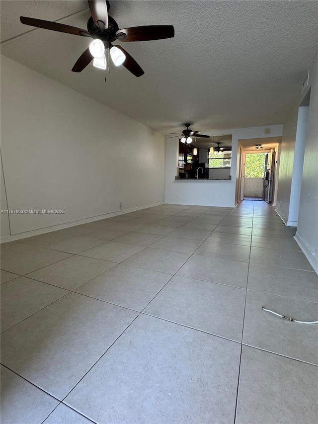 interior space featuring baseboards, a textured ceiling, and a ceiling fan