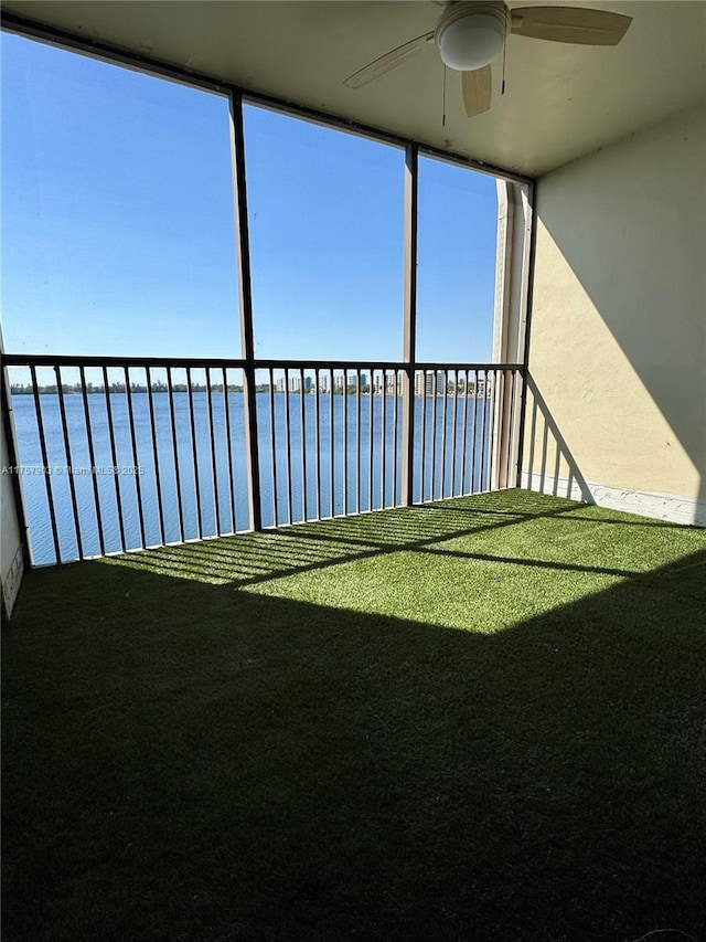 view of yard with a balcony, a water view, and ceiling fan