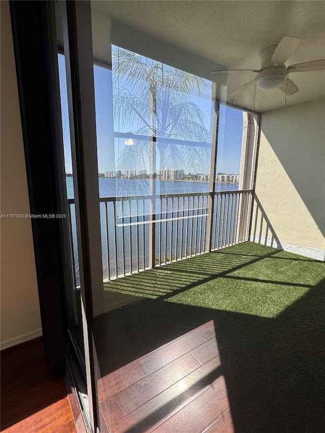 balcony featuring ceiling fan and a water view