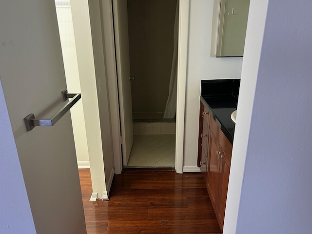 hall featuring dark wood-style flooring and baseboards