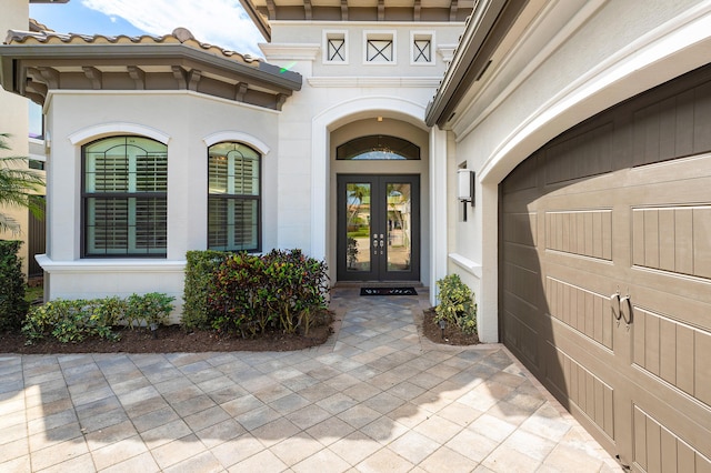 doorway to property with stucco siding, french doors, driveway, and a garage