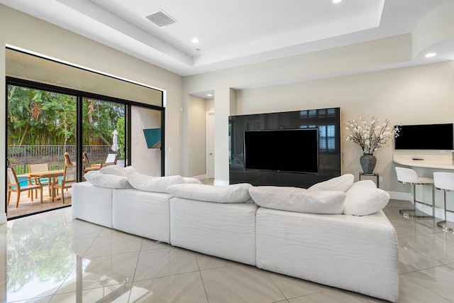 living area with visible vents, a tray ceiling, recessed lighting, light tile patterned flooring, and baseboards