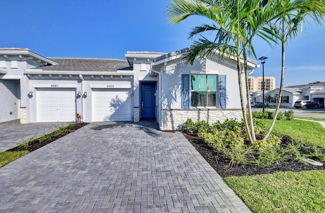 6975 Peters Ln, Delray Beach, FL 33446 - view of front of property with stone siding, a garage, decorative driveway, and stucco siding