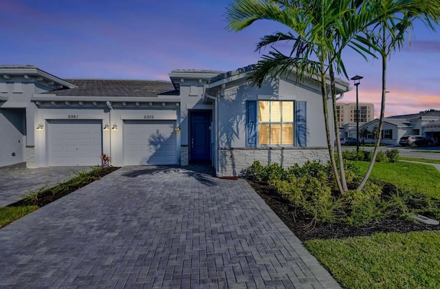 6975 Peters Ln, Delray Beach, FL 33446 - view of front of house with decorative driveway, a garage, stone siding, and stucco siding