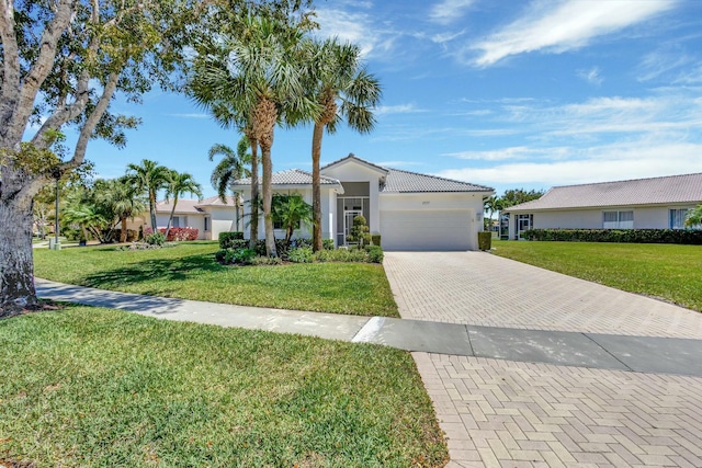2737 Clipper Cir, West Palm Beach, FL 33411 - mediterranean / spanish-style home featuring a garage, decorative driveway, a front yard, a tile roof, and stucco siding