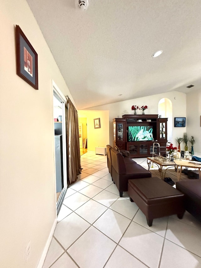 434 SE Doat St, Port Saint Lucie, FL 34983 - living area featuring a textured ceiling, baseboards, arched walkways, vaulted ceiling, and light tile patterned floors