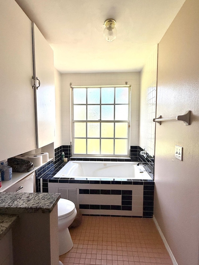 434 SE Doat St, Port Saint Lucie, FL 34983 - bathroom with tiled bath, toilet, and tile patterned floors