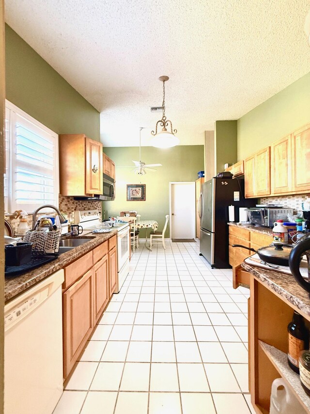 434 SE Doat St, Port Saint Lucie, FL 34983 - kitchen with lofted ceiling, light tile patterned floors, stainless steel appliances, backsplash, and a ceiling fan