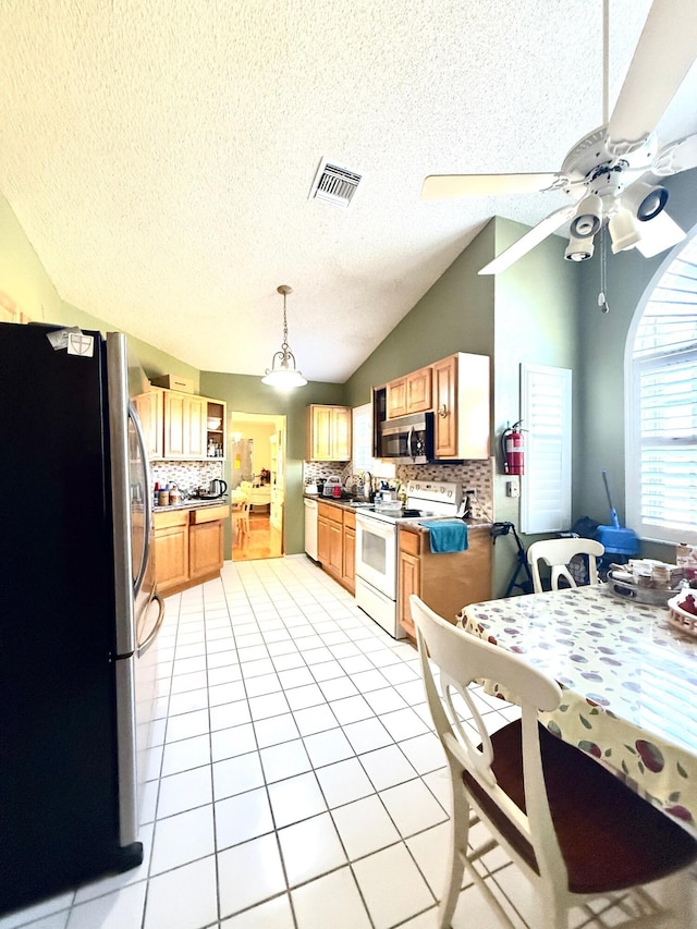 434 SE Doat St, Port Saint Lucie, FL 34983 - kitchen with visible vents, ceiling fan, stainless steel appliances, vaulted ceiling, and light tile patterned floors