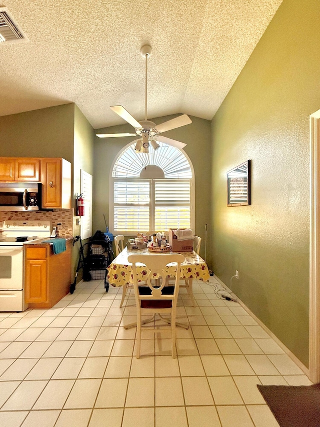434 SE Doat St, Port Saint Lucie, FL 34983 - dining area featuring visible vents, a ceiling fan, a textured wall, vaulted ceiling, and light tile patterned floors